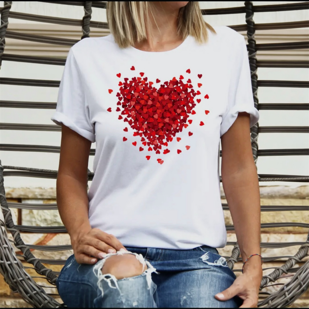 Person wearing a white t-shirt with a red heart design, sitting on a wicker chair.