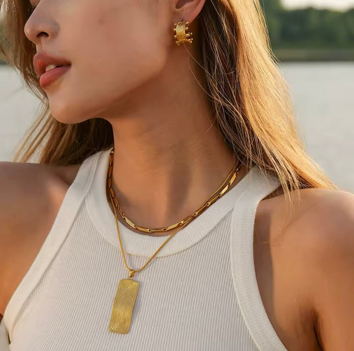Close-up of a woman wearing gold jewelry with a blurred natural background