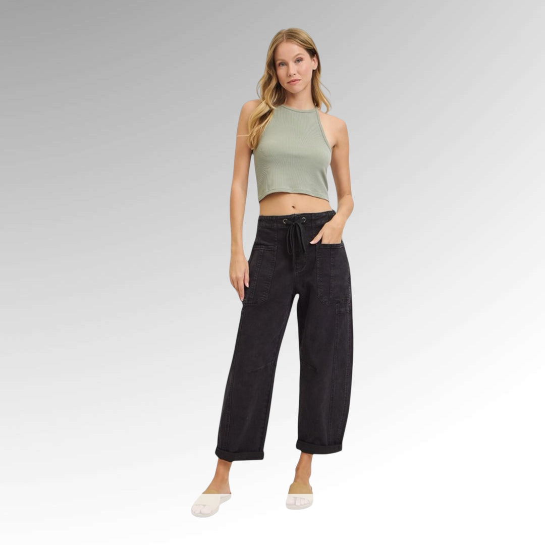Woman wearing a green crop top and black pants on a gray background
