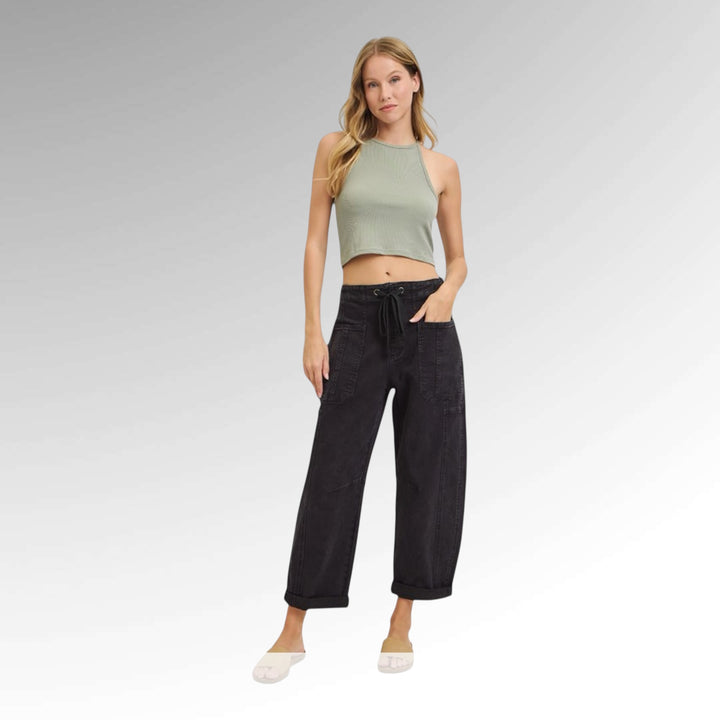 Woman wearing a green crop top and black pants on a gray background