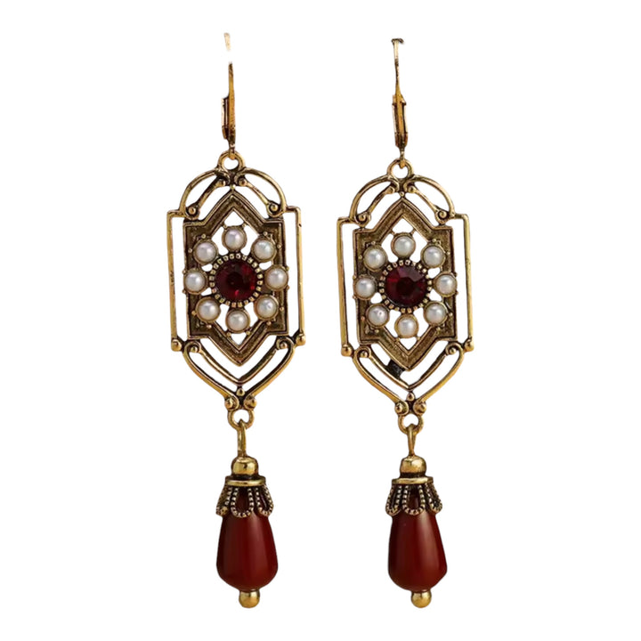 Pair of ornate earrings with gold frames, red beads, and pearl-like stones on a white background.