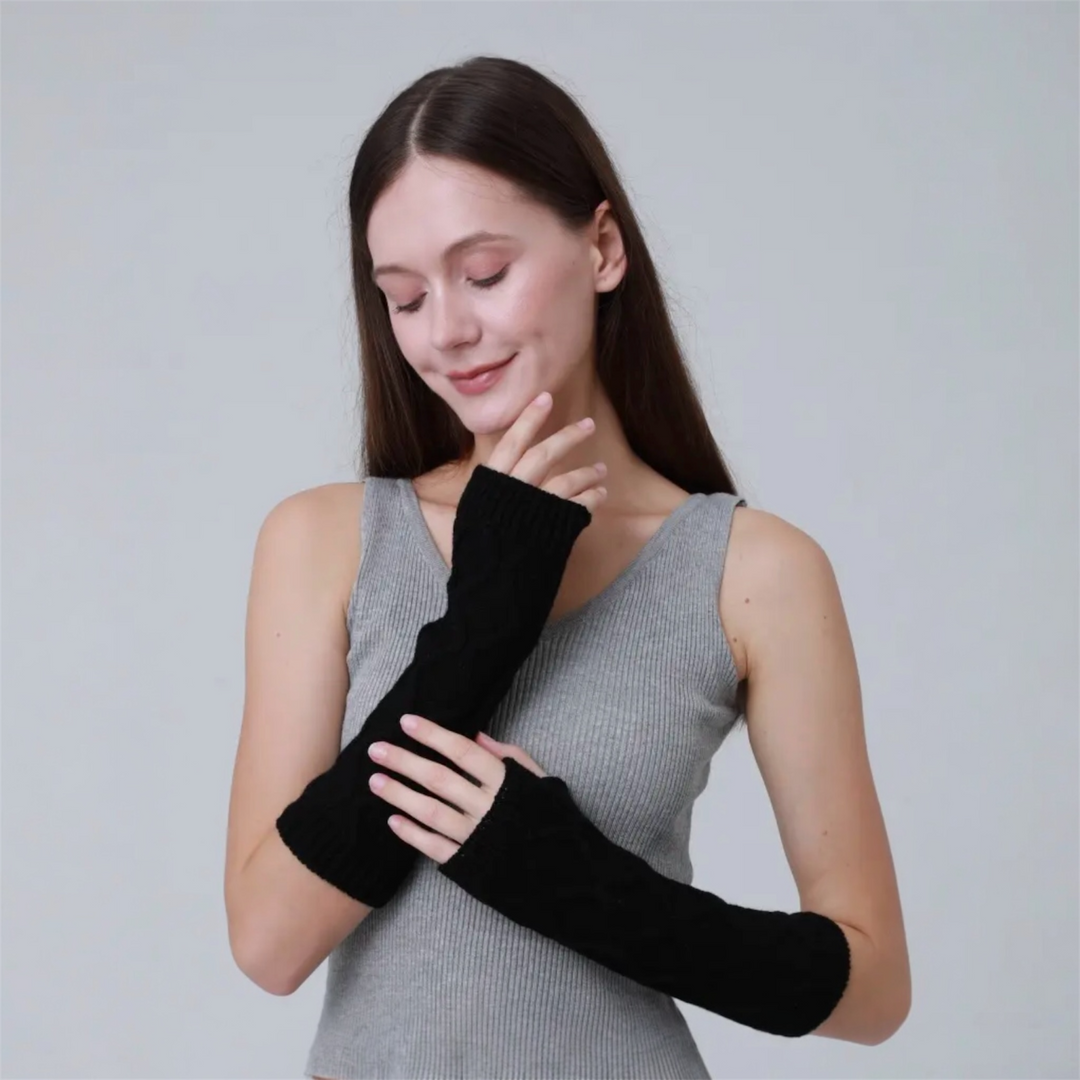 Woman wearing black wrist warmers against a light gray background