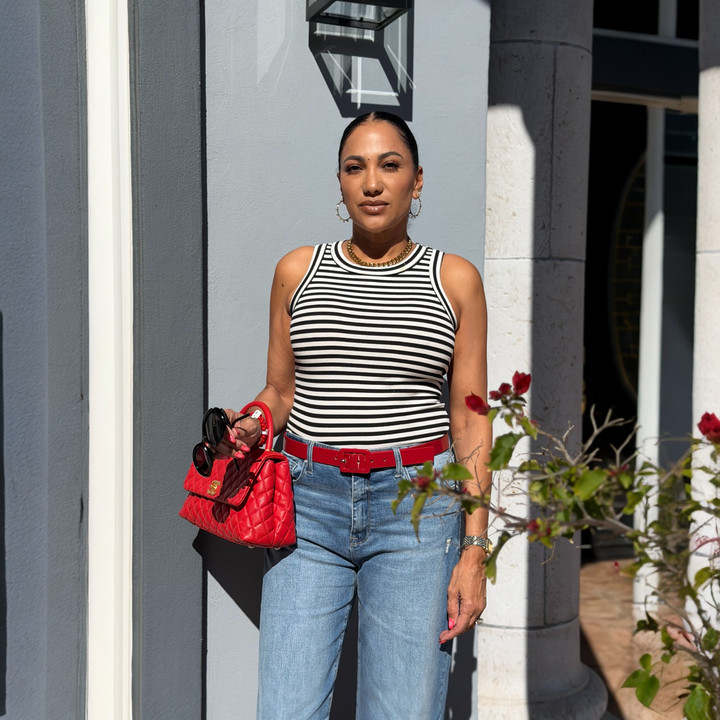 Woman in striped top and jeans holding a red handbag outdoors.