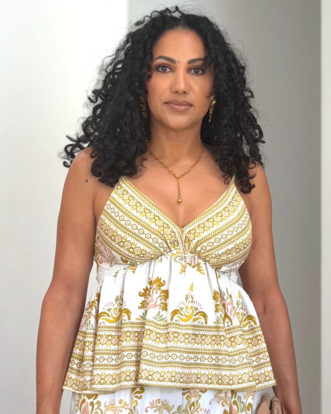 Ivory and gold baroque print peplum cami top with adjustable straps and smocked back, styled with matching wide-leg pants, available at Butterfly Alley Boutique.