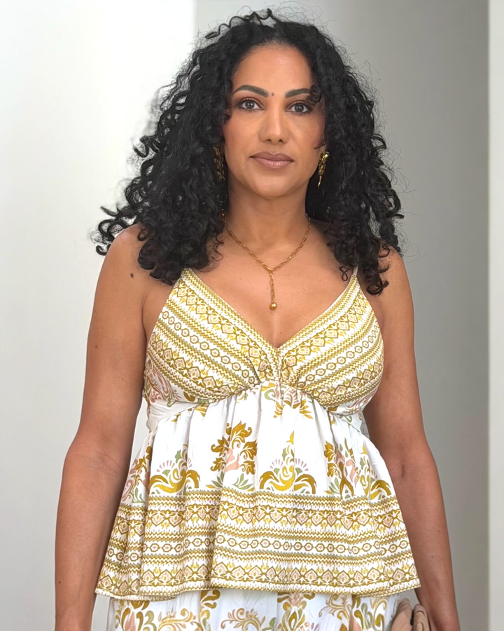 Ivory and gold baroque print peplum cami top with adjustable straps and smocked back, styled with matching wide-leg pants, available at Butterfly Alley Boutique.