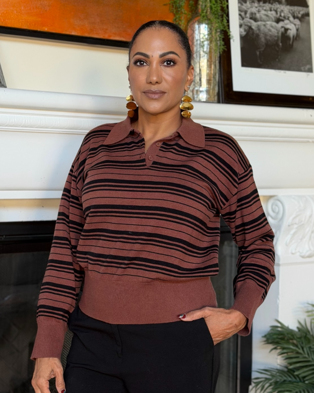 Brown and black striped polo sweater with ribbed waist styled with black trousers and a tan handbag.