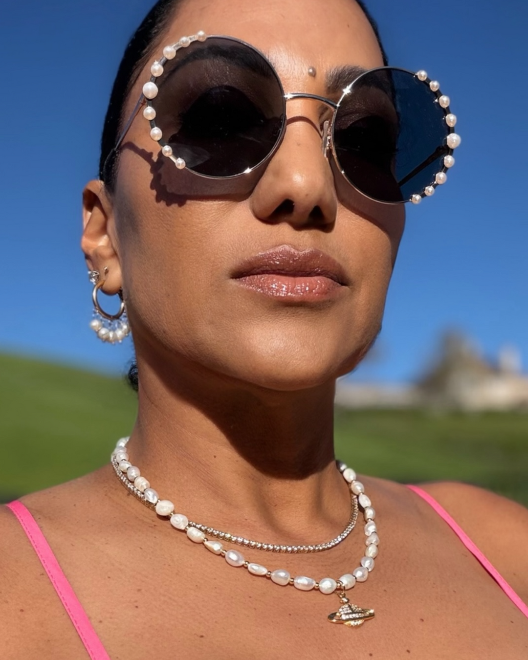 Silver hoop earrings with pearl accents, styled with layered pearl necklaces and pearl-trimmed sunglasses.