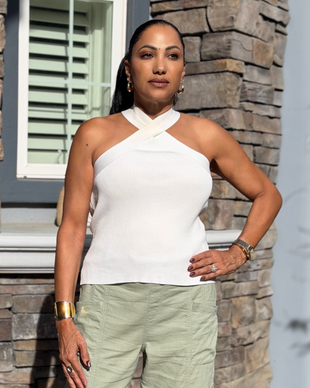 White ribbed cross-neck halter top styled with sage green cargo pants and gold jewelry, modern chic women’s boutique outfit.