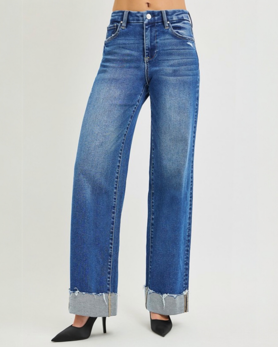 Plus size high-rise wide leg blue jeans with cuffed frayed hem styled with black heels.