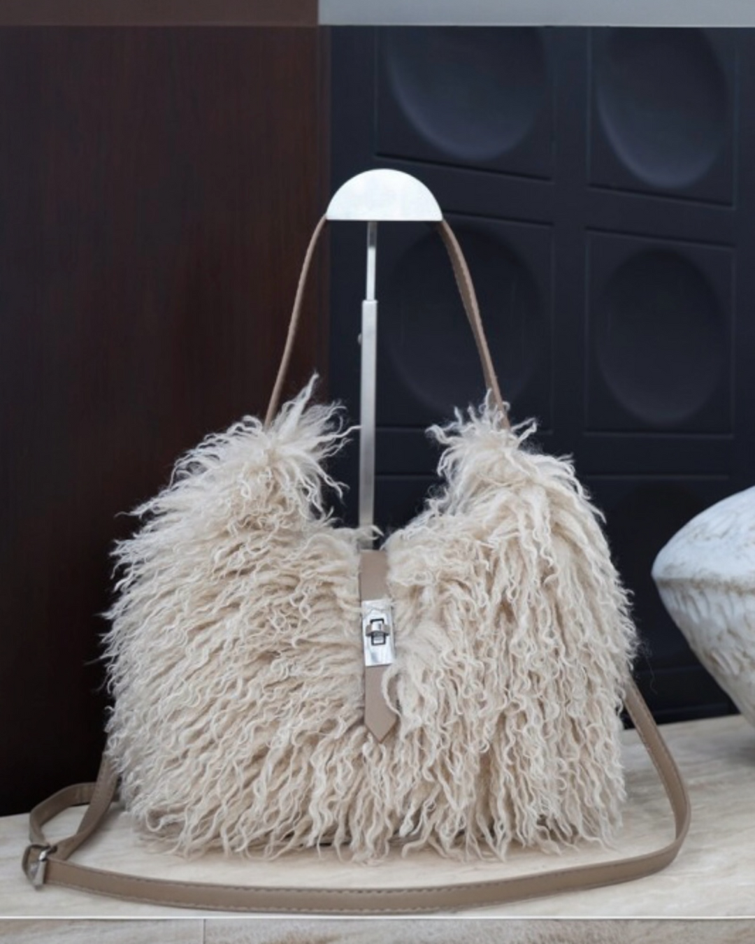 Cream faux shearling textured shoulder bag with detachable crossbody strap and metal clasp closure.
