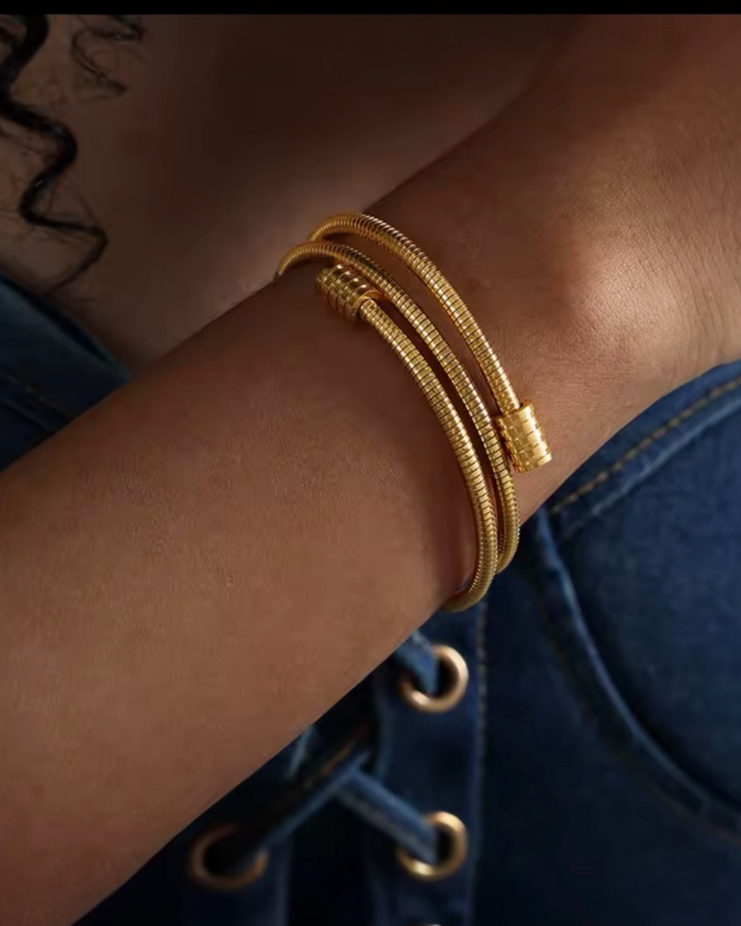 Gold and silver multi coil cuff bracelet with modern layered design worn on wrist.