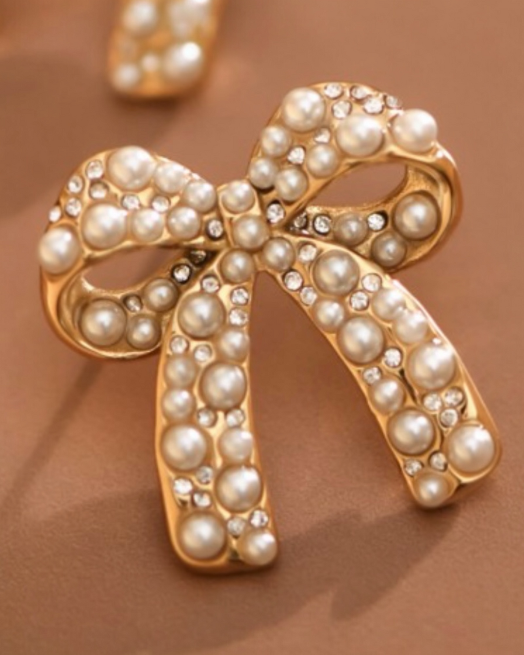 Gold bow earrings adorned with faux pearls and crystal accents in a vintage-inspired design.