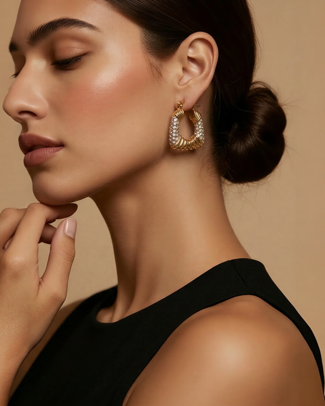 Gold pavé crystal hoop earrings with sculptural design and hinge closure.