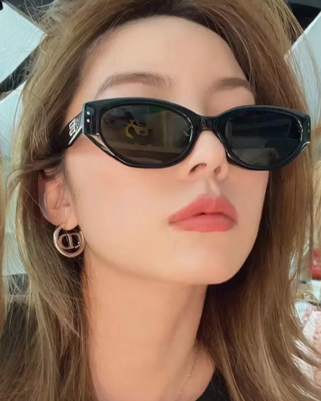 Black cat-eye sunglasses with dark lenses and glossy frame worn by model.