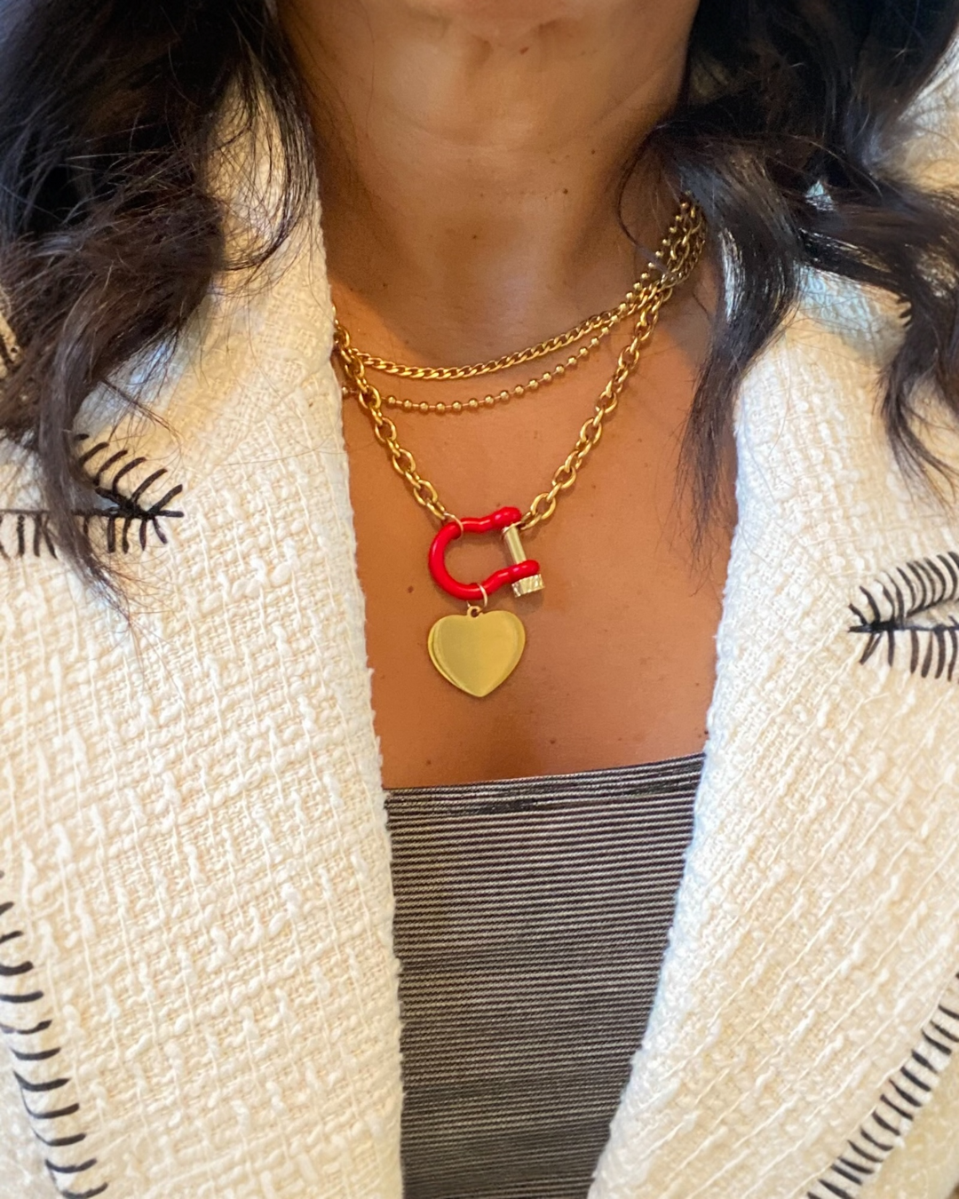 Necklace with red and gold heart pendants worn by a person