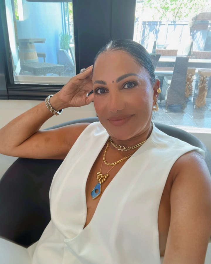 Woman in a white dress with lapis necklace jewelry sitting in an outdoor setting