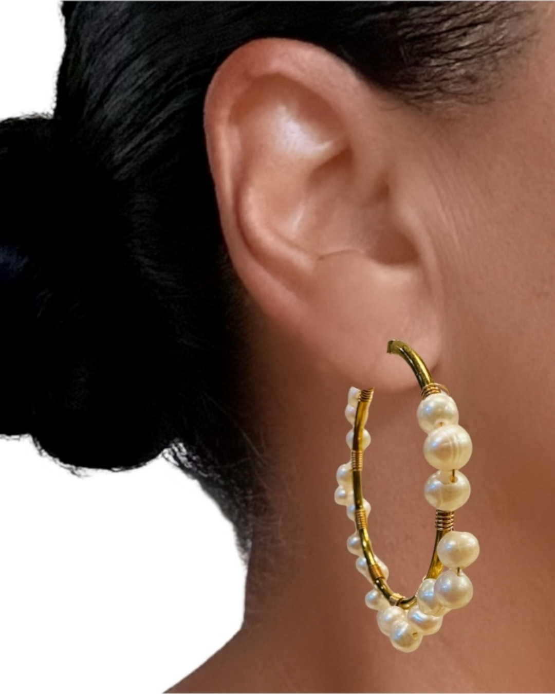 Pearl hoop earring worn by a person with a neutral background