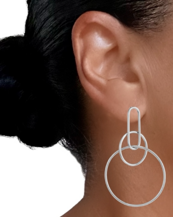 Silver hoop earrings worn by a person with dark hair tied back.