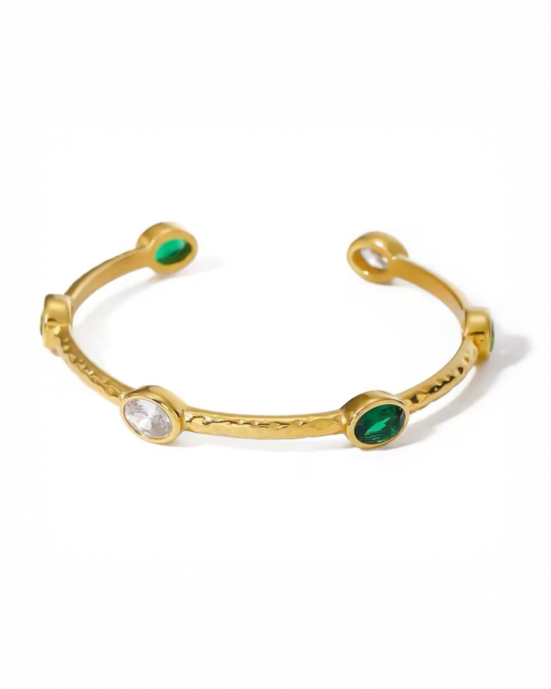 Gold open cuff bracelet with a textured band, featuring bezel-set round green and clear stones spaced along the design, creating a modern, elegant look.