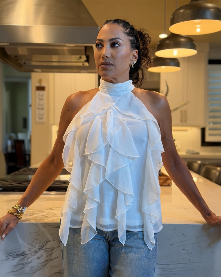 Woman wearing a white ruffled top in a kitchen setting
