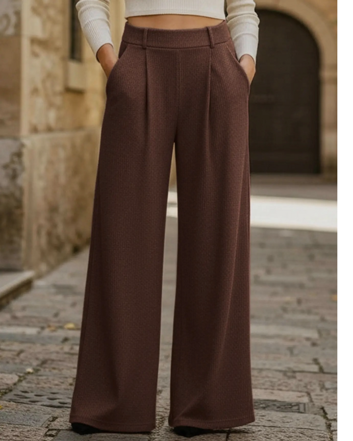 Brown wide-leg pants worn by a person on a stone pavement.