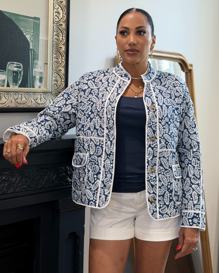 Woman wearing a blue and white patterned quilted jacket indoors.