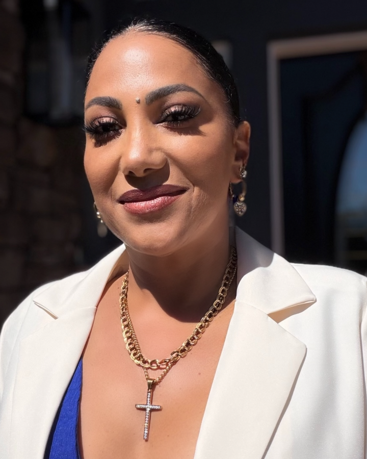 Woman wearing a white blazer and gold chain with a cross pendant