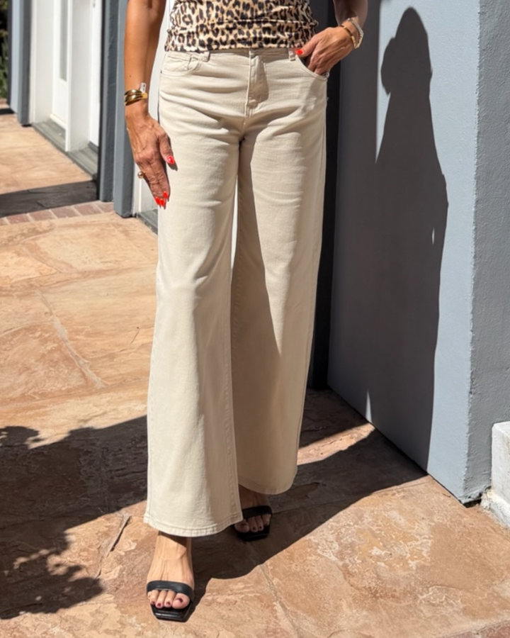 woman wearing white wide-leg pants and a leopard print top outdoors.