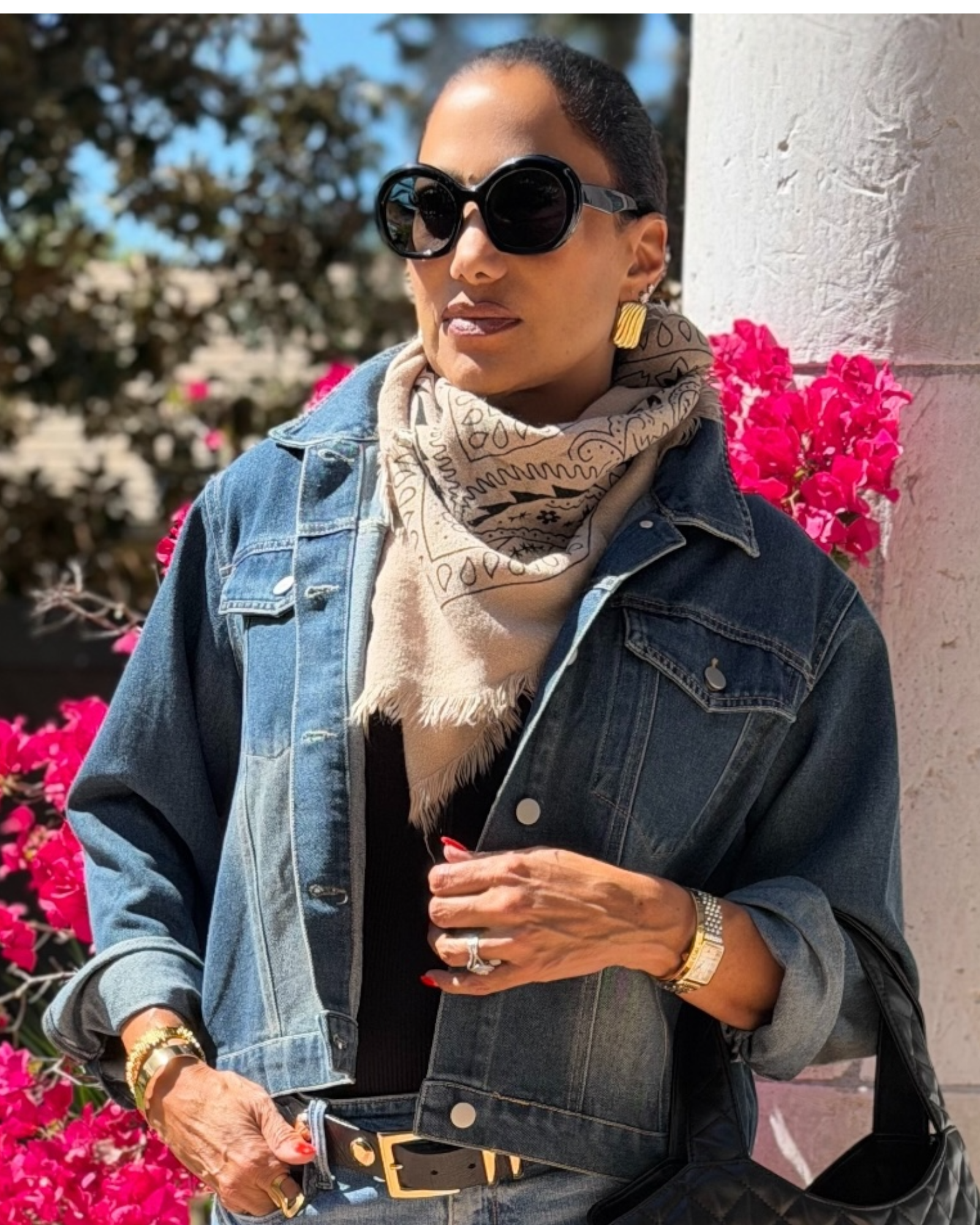 Woman wearing a denim jacket and bandana scarf with pink flowers in the background