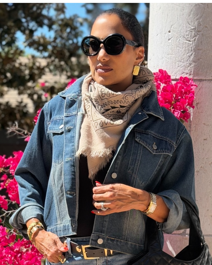 Woman wearing a denim jacket and bandana scarf with pink flowers in the background
