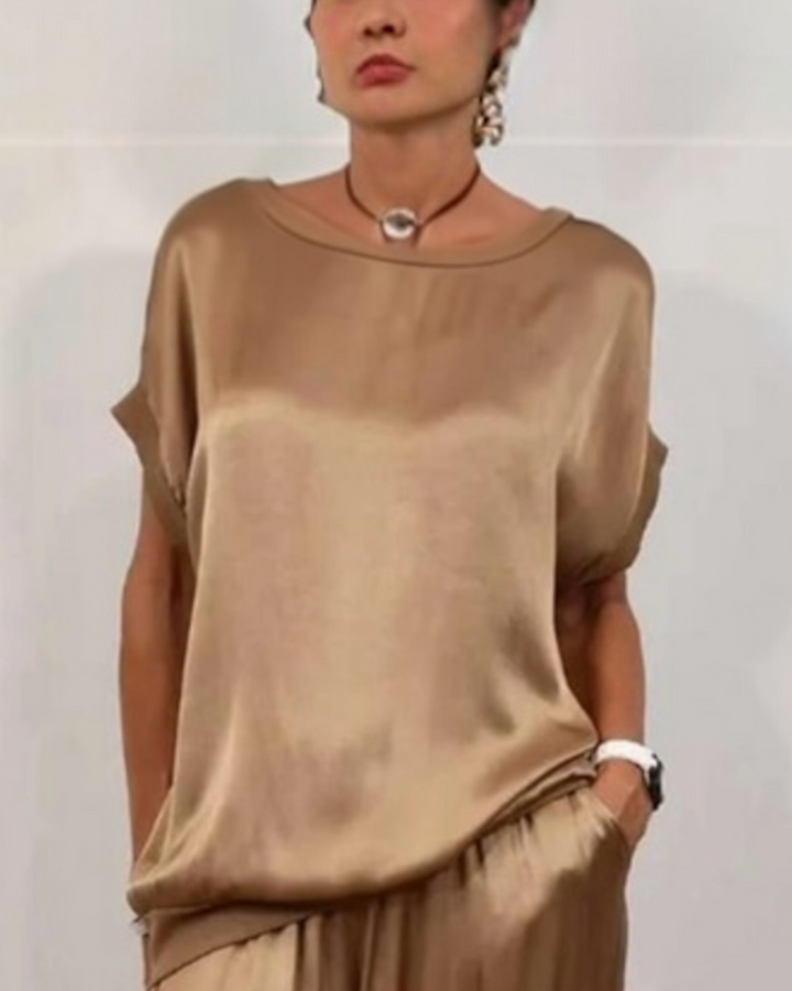 Person wearing a beige satin top and pants against a plain background