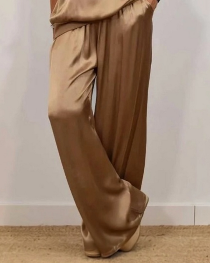 Brown satin pants worn by a person on a plain background