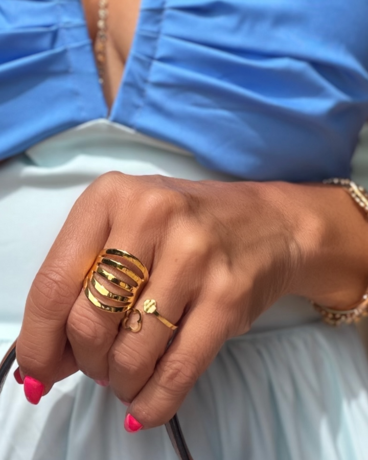 Close-up of a hand wearing gold rings with a blue background