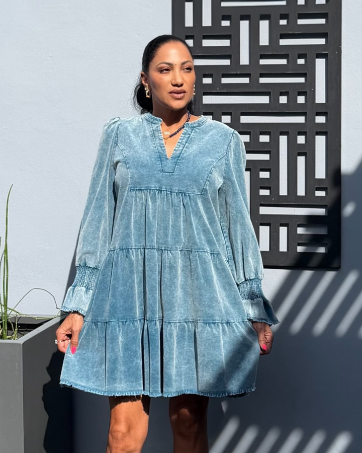 Woman wearing a light blue dress standing against a geometric wall.