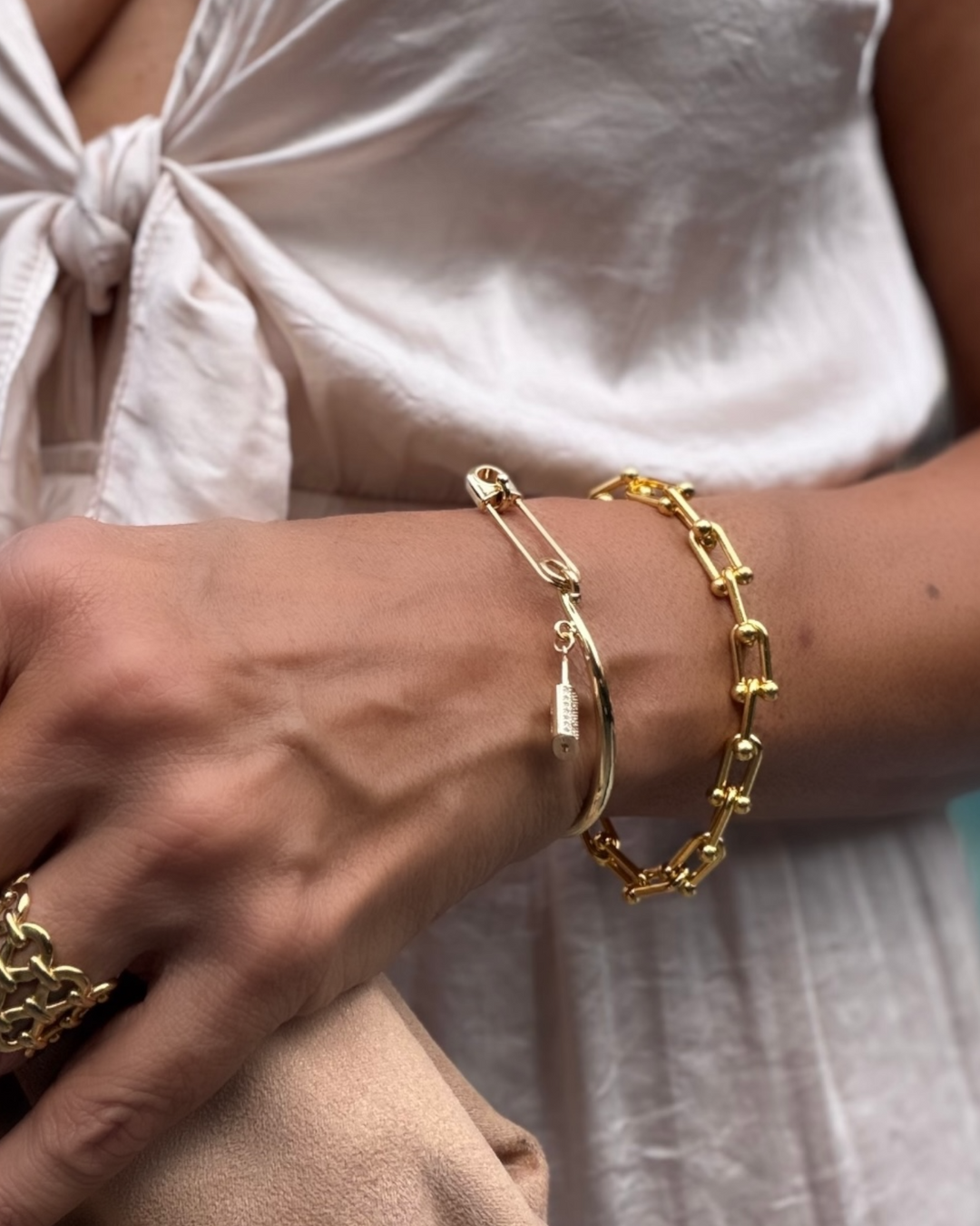 Gold bracelets on a wrist with a light background