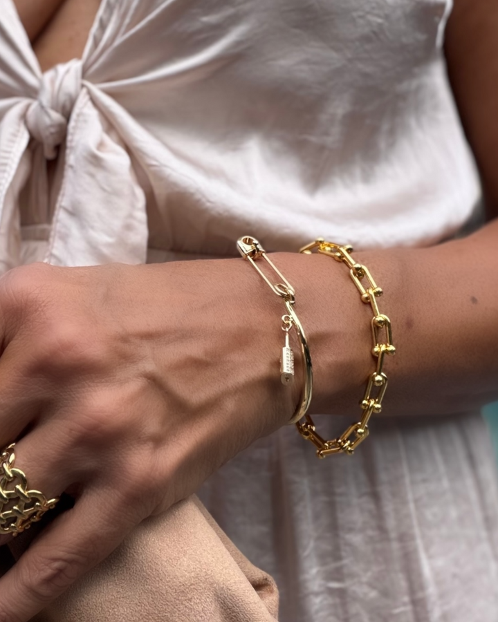 Gold bracelets on a wrist with a light background