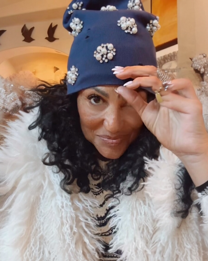 Navy blue knit beanie with pearl and rhinestone embellishments styled for a chic winter look, adding a glam touch to a cozy outfit