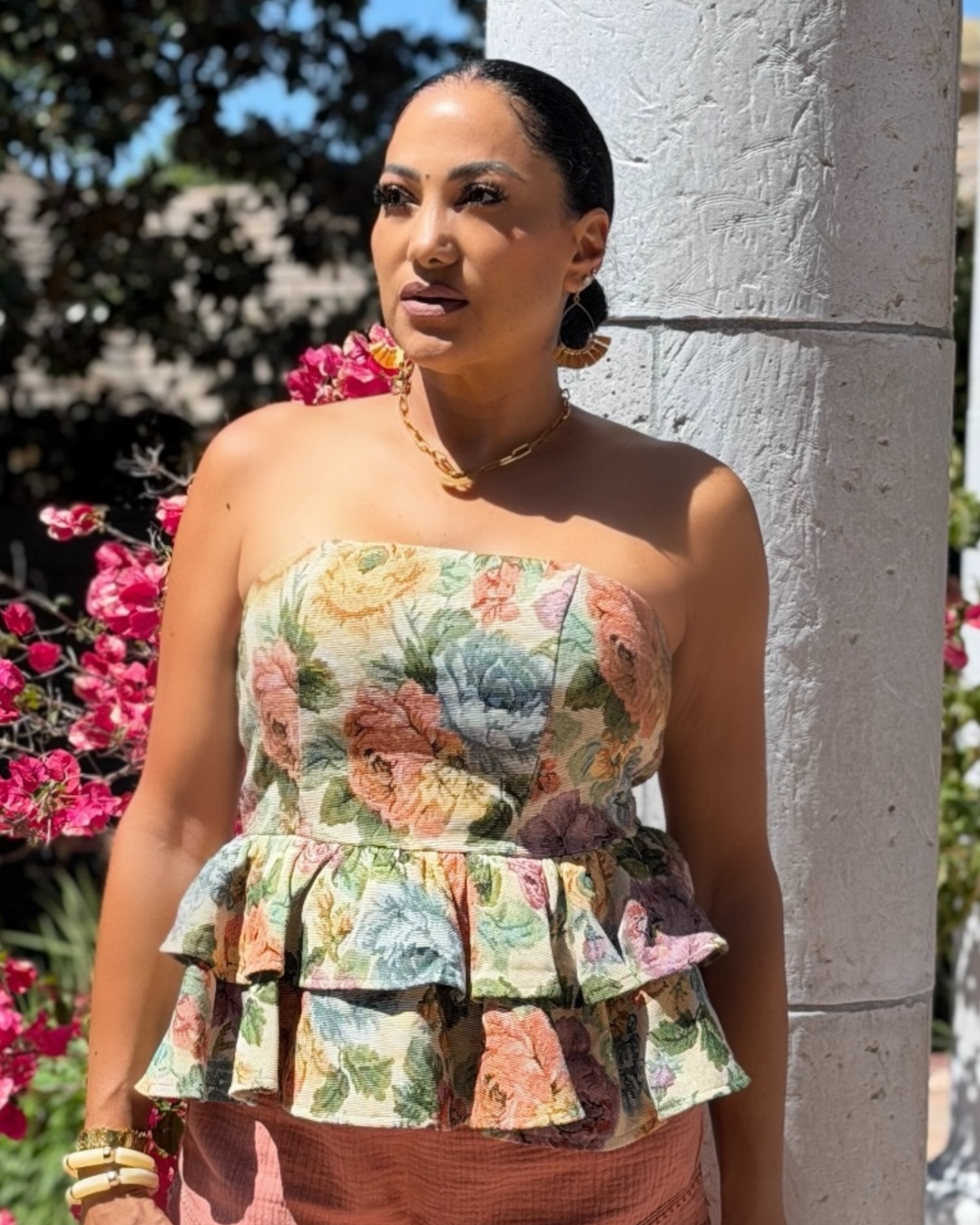 Woman modeling a strapless vintage floral peplum tube top with ruffle hem and smocked back, styled with dusty rose shorts and denim jeans for a chic summer outfit.
