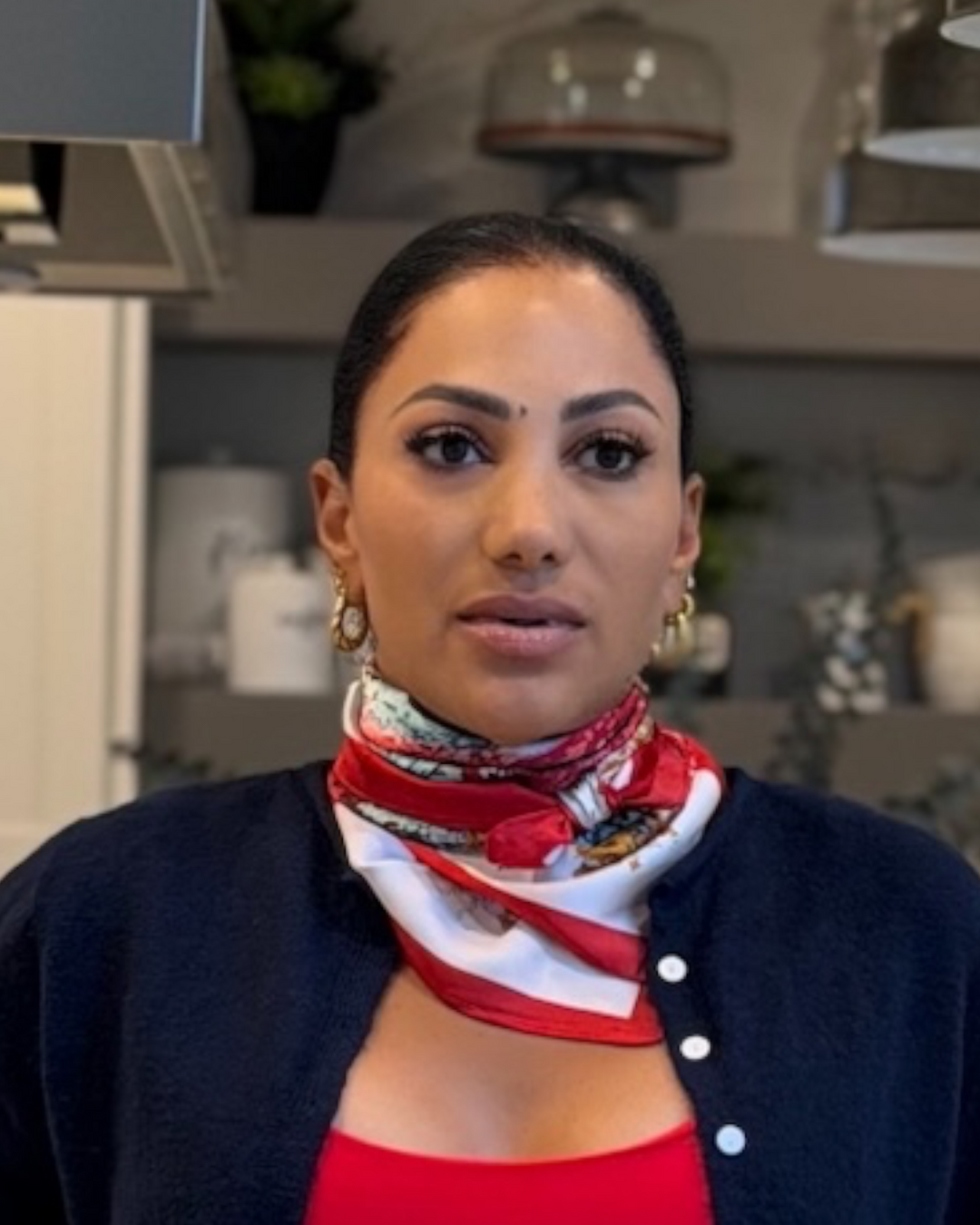 Woman wearing red and white floral Wildflower Scarf tied as a neck bandana with navy cardigan