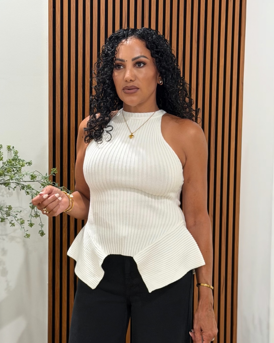 Woman wearing white ribbed knit halter top with peplum hem and black wide-leg pants