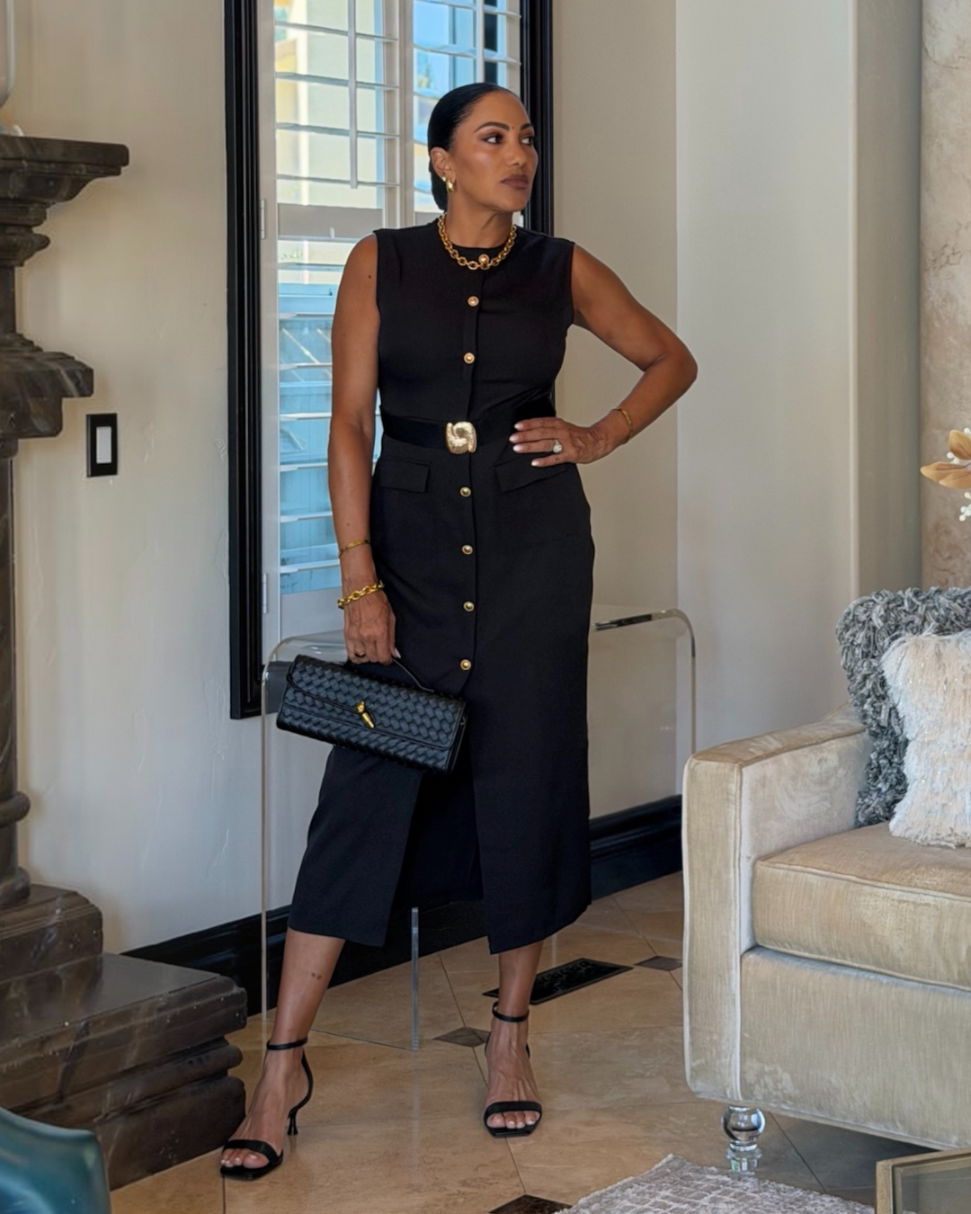 model wearing black button-front midi dress with sculptural gold belt buckle