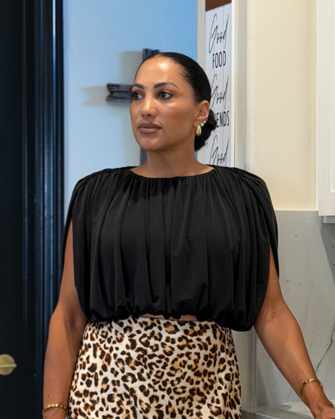 model wearing black balloon top with gathered neckline, styled with a leopard print skirt