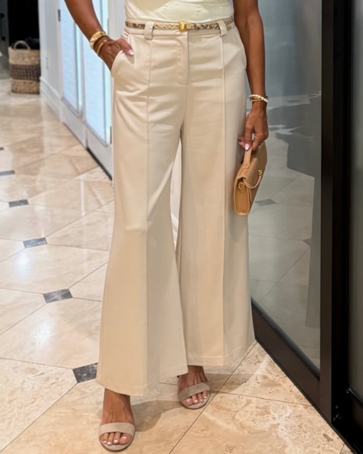 model wearing cream wide leg trouser with front closure and side pockets, styled with a woven belt