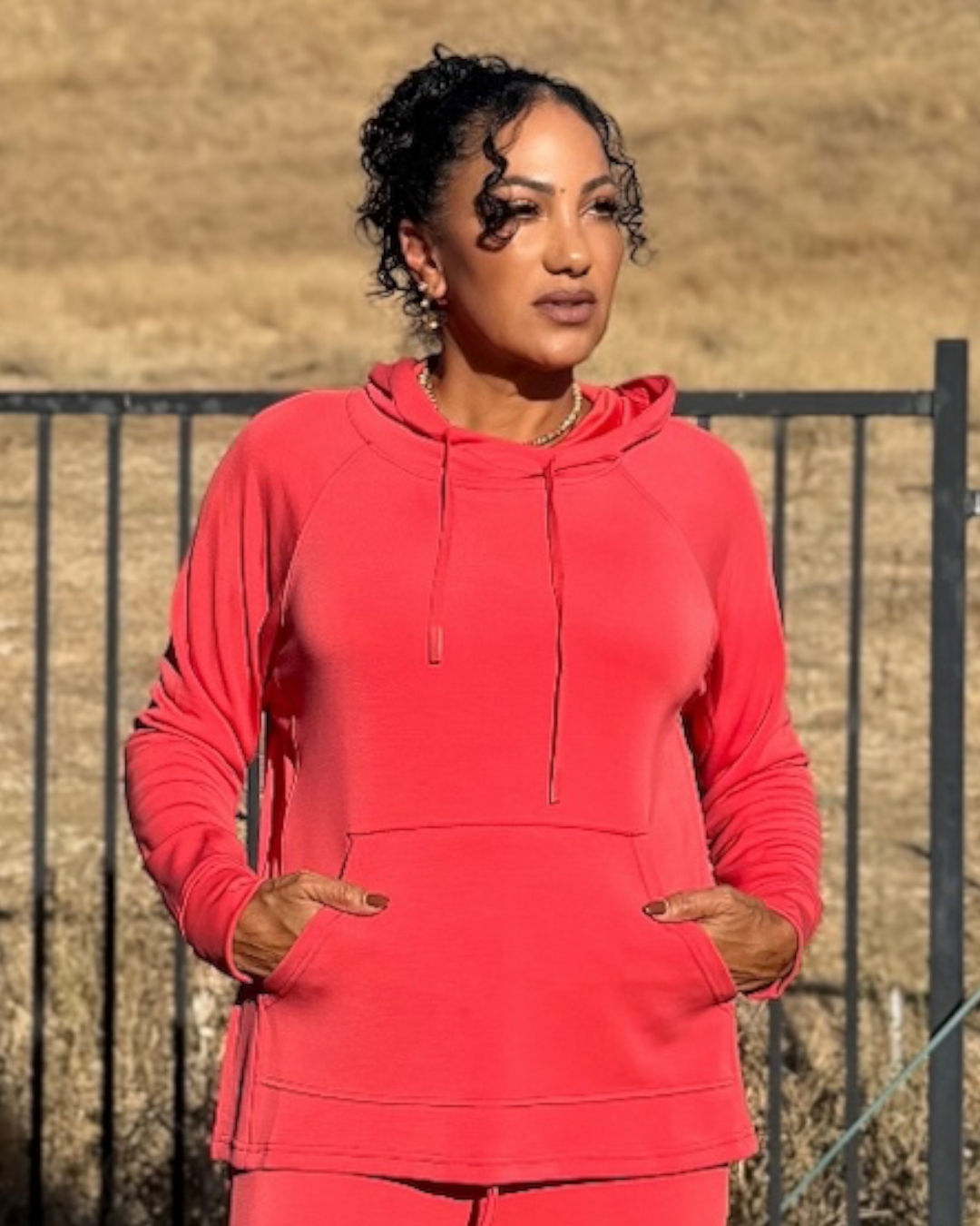 Front view of Mira Blushed Brick hooded pullover with the hood up, drawstring, and kangaroo pocket