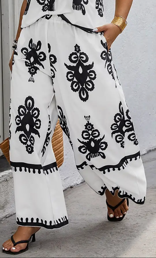 White pants with black patterns worn by a person against a light gray wall.