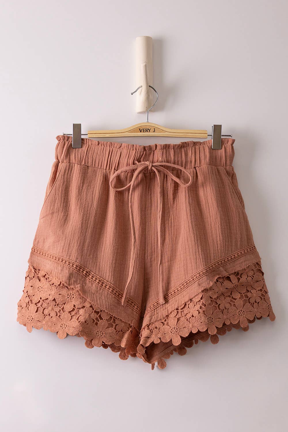 Woman wearing lightweight woven shorts with lace trim detailing, featuring an elastic drawstring waist and relaxed fit.